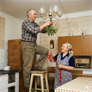 Aktivizace senioři s demencí – Senior zavěšuje jmelí v kuchyni, partnerka drží stuhu – Aktivizace senioři s demencí